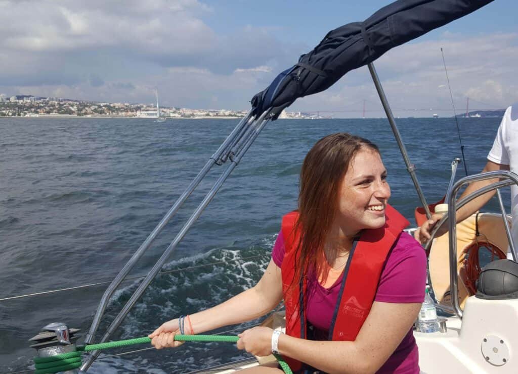 Chica tirando de los cables del velero durante una regata