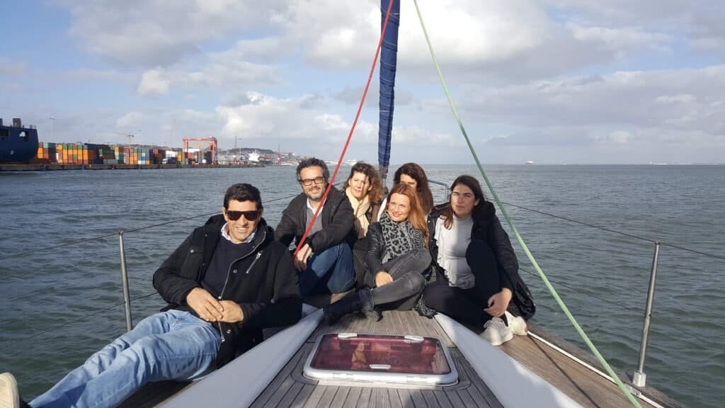 Passeio de barco no rio Tejo ao final de tarde com amigos na proa do barco