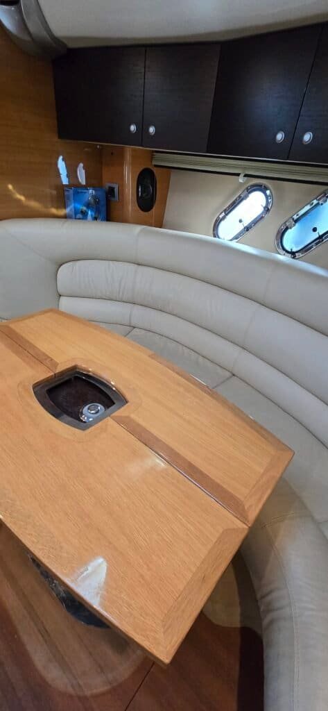 Interior acolhedor do iate com sofá em U e mesa de madeira, perfeito para refeições ou momentos de lazer
