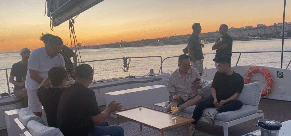 Invitados en la zona superior del velero catamarán con vistas a Lisboa y la puesta de sol.