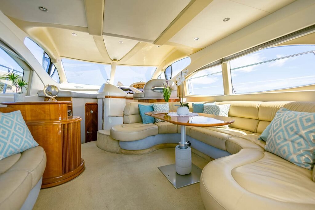 Interior luxuoso do iate Azimut 46 com sofá em U, mesa central e acabamentos em madeira.