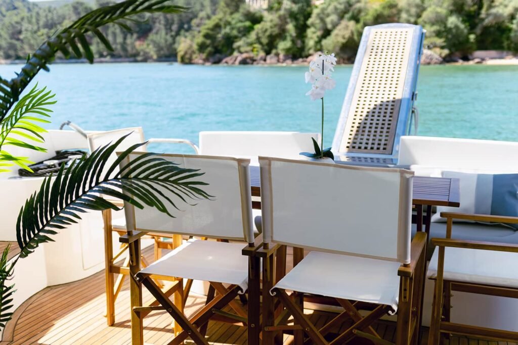 Mesa de refeições exterior na popa de um iate de luxo Azimut 46 com cadeiras brancas.