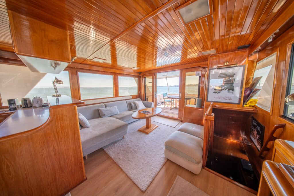 Salão interior do iate Trawler Alexander 56, com acabamentos elegantes em madeira, janelas panorâmicas, sofás modernos e ambiente ideal para relaxar durante o passeio.